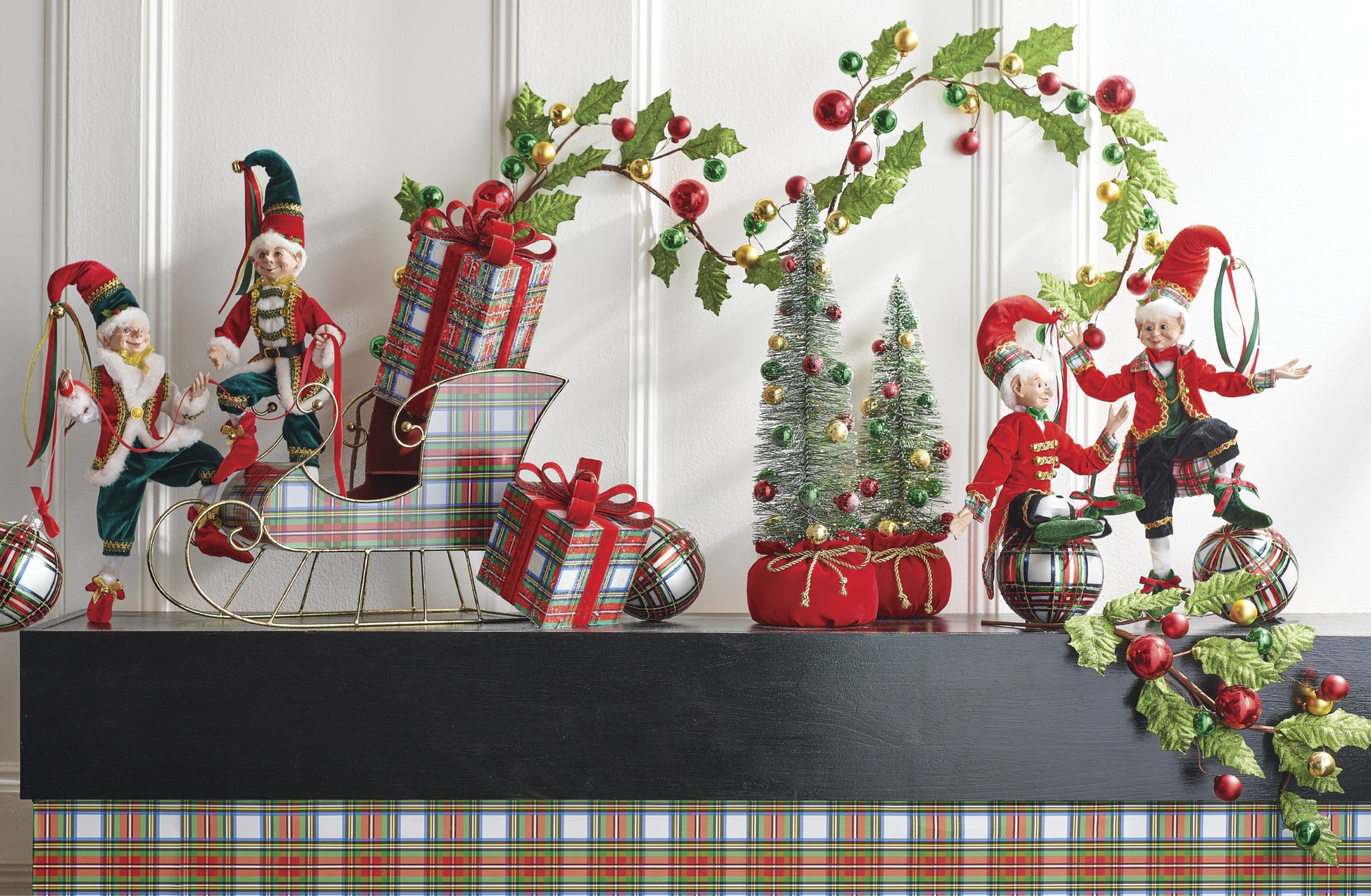 10" Plaid Package Ornaments. Set of 2. Red and white with green, blue, and yellow plaid print. Red bow and jingle bell on top. Made of Foam and Polyester. Placed on a mantel surrounded by elves and holly jolly décor and ornaments.